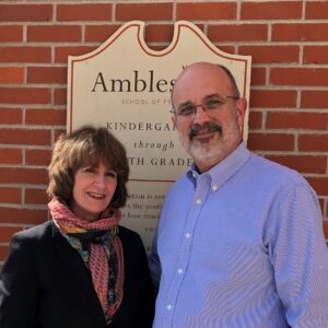 Pg 16 About Us-Our History-Maryellen and Bill in front of Plaque